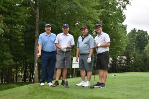 Four people standing together with golf clubs 